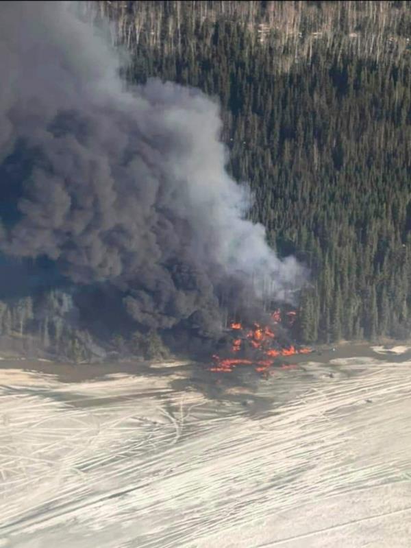 A fire burns after a Douglas C-54 Skymaster plane crashed into the Tanana River.