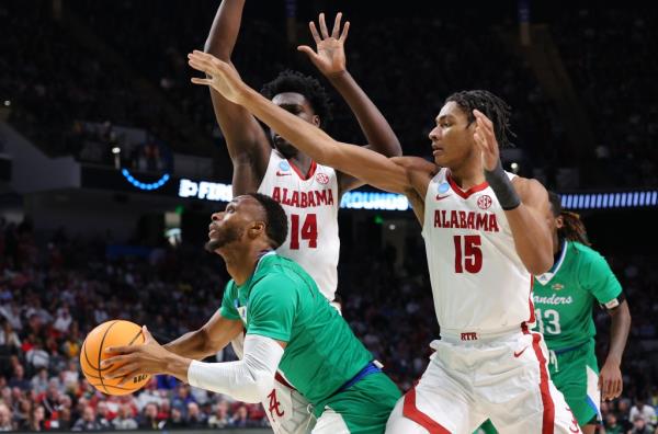 Isaac Mushila #10 of the Texas A&M-CC Islanders looks to shoot the ball against Charles Bediako #14 and Noah Clowney #15 of the Alabama Crimson Tide