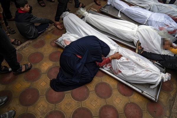 A woman mourns the covered bodies of her child and her husband killed in an Israeli army bombardment of the Gaza Strip, in the hospital in Khan Younis, Tuesday Dec. 5, 2023.