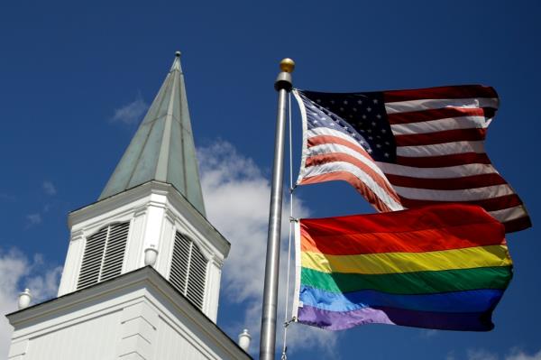 A gay Pride rainbow flag flies with the U.S. flag in front of the Asbury United Methodist Church in Prairie Village, Kan., on Friday, April 19, 2019.