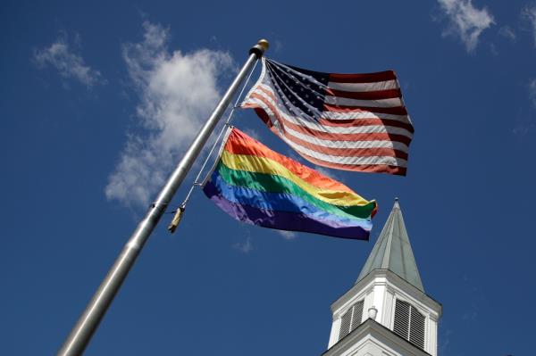 A gay Pride rainbow flag flies with the U.S. flag in front of the Asbury United Methodist Church in Prairie Village, Kan., on Friday, April 19, 2019.