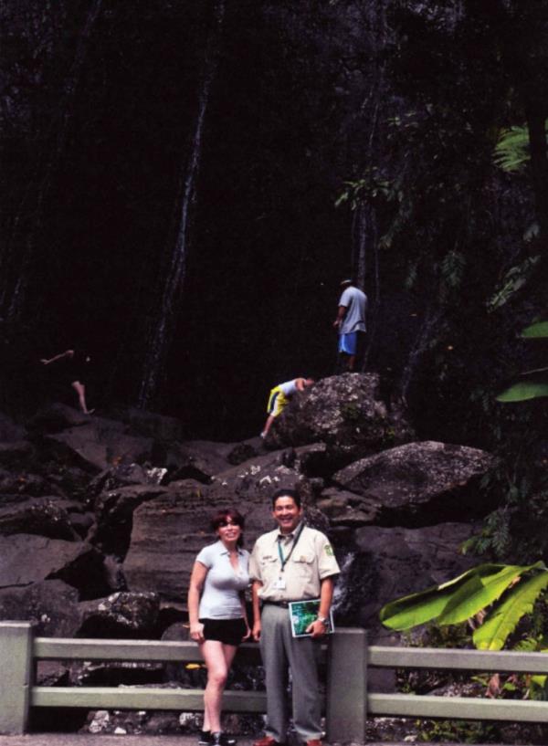 Cecilia Reynolds with a man in the uniform of the United States Forest Service, in front of rocks and tropical plants