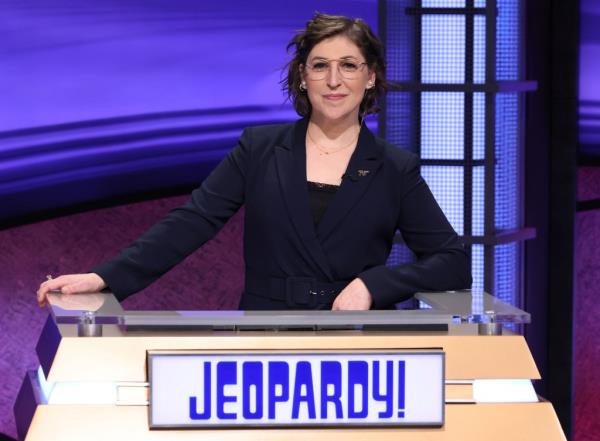 Mayim Bialik stands at a podium that reads 