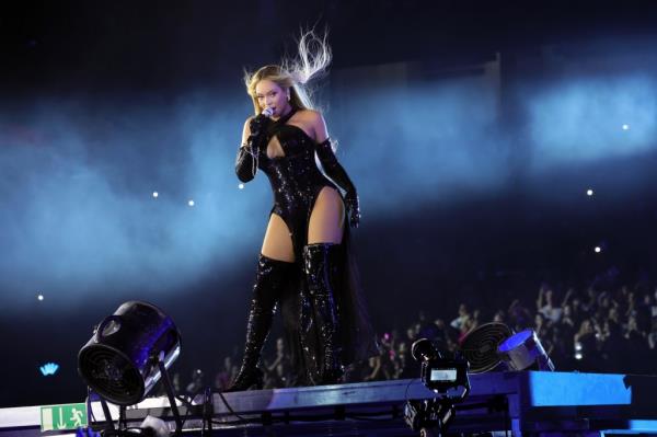 Beyoncé performs on stage in a black glitter body suit and thigh-high black boots.