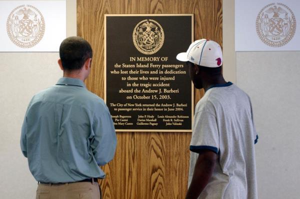 Staten Island Ferry passengers, aboard the Ferryboat Andrew J. Barberi, view a plaque dedicated to the victims of the Oct. 2003 crash early Thursday, July 1, 2004 in New York. 