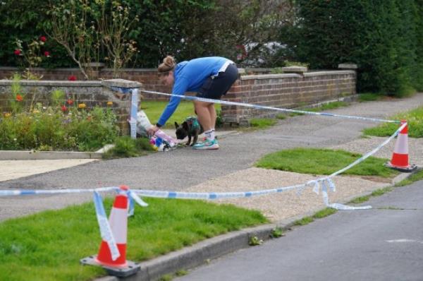 A person leaves flowers outside a property on Hammond Road in Woking, Surrey, wher<em></em>e a 10-year-old girl was found dead after officers were called to the address on Thursday following a co<em></em>ncern for safety. Picture date: Friday August 11, 2023. PA Photo. See PA story POLICE Woking. Photo credit should read: Jo<em></em>nathan Brady/PA Wire