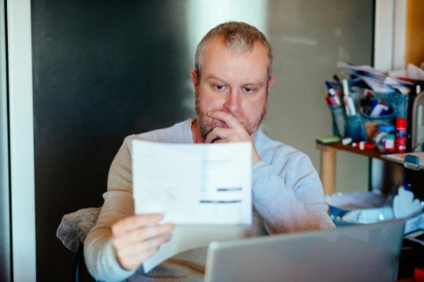 Worried man checking bills at home