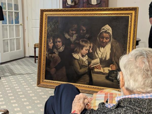 Schoolmistress painting, which depicts a teacher sitting at a table surrounded by young students