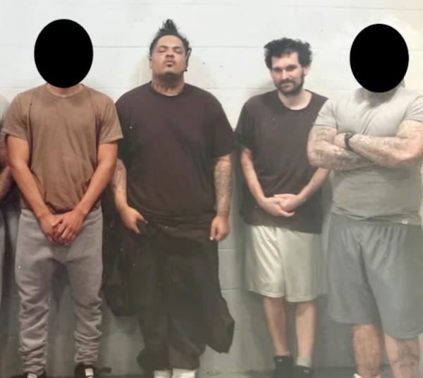 Sam Bankman-Fried in Metropolitan Detention Center, sporting a beard and standing with five fellow inmates, former gang members included, awaiting sentencing for his cryptocurrency crimes