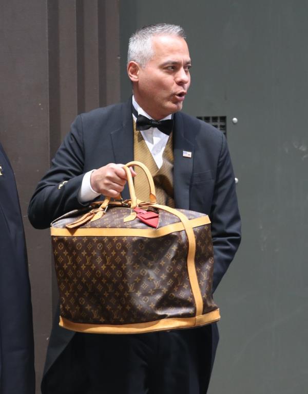 A doorman holds the Louis Vuitton luggage.