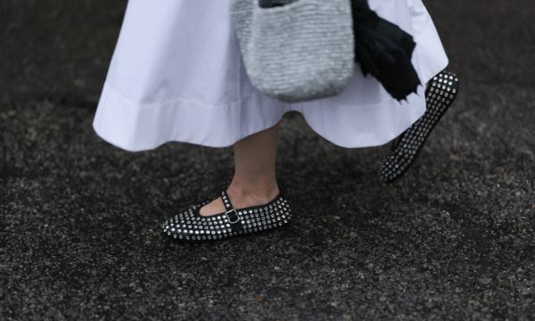 Guest at New York Fashion Week 2023 wearing white maxi dress, silver necklace, silver studed Alaia ballet flats and carrying a silver handbag