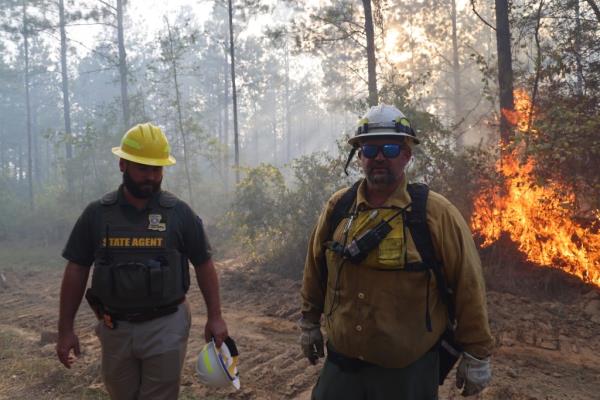 Firefighters are pictured on the fro<em></em>ntlines with a fire behind them.