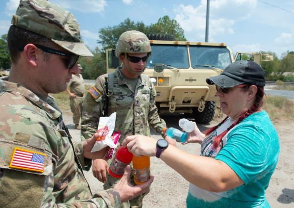 Volunteer Christina Brumley, right, drops off snacks and cold drinks to Army Natio<em></em>nal Guard members Brian Aucoin, center, and Jacob Cox.