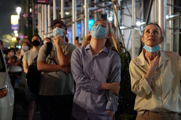 Small crowd wearing face masks watching the Macy's Fourth of July fireworks display near the Empire State Building in New York City. 