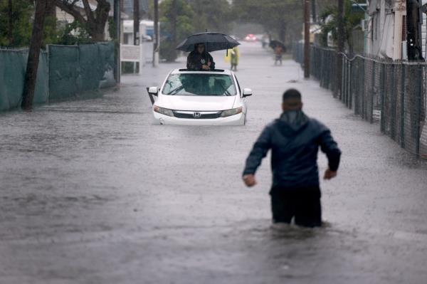 A person waits for help in a stalled vehicle sitting in the flooded street on June 12, 2024, in Hallandale Beach, Florida.