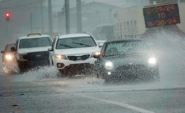 Cars push through flood waters after heavy rain on Wednesday, June 12, 2024, in Oakland Park, Fla.