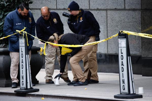 Members of the New York police crime scene unit pick up cups marking the spots wher<em></em>e bullets lie as they investigate the scene outside the Hilton Hotel in midtown Manhattan