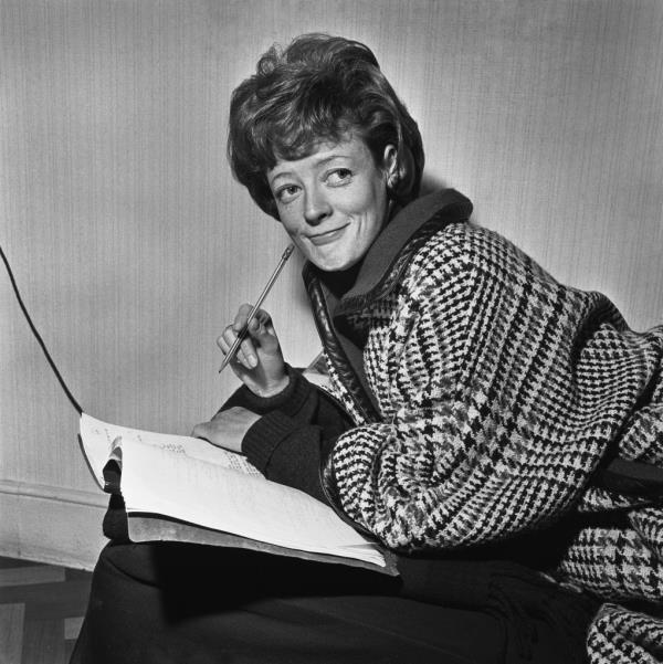 Maggie Smith wearing a dogtooth check outfit, leaning over an open docu<em></em>ment, possibly a s<em></em>cript, with a pencil in her hand, United Kingdom, 22nd January 1963. 