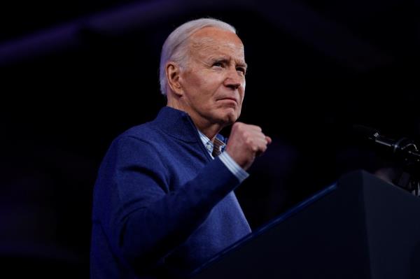 Joe Biden gesturing at a campaign event, standing at a podium in front of an audience at Strath Haven Middle School in Wallingford, Pennsylvania.