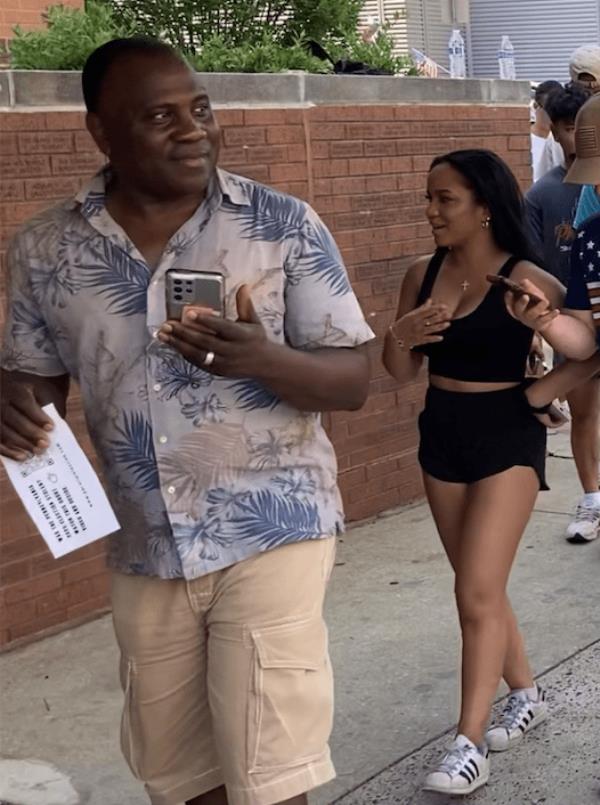 Black Trump supporters walking on a sidewalk, unbothered by a protest message