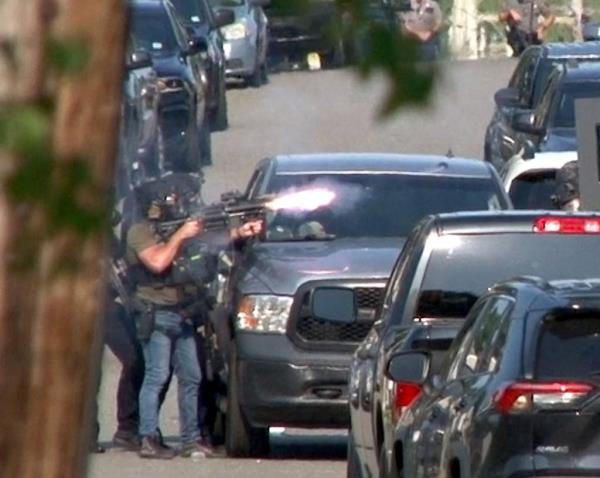 SWAT officer firing a cannister into a house on Ravenwood Drive during a standoff situation