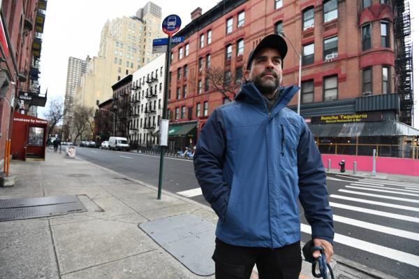 A man, Jayme Ribeiro, standing on a sidewalk in Hell's Kitchen, talking with the NY Post. Photo by Matthew McDermott.