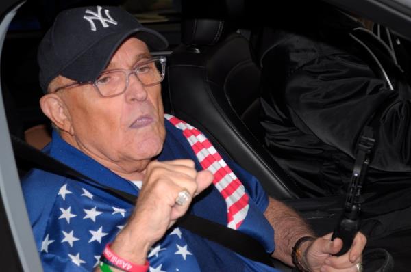 Former New York City mayor, Rudy Giuliani drives past protesters near Columbia University.