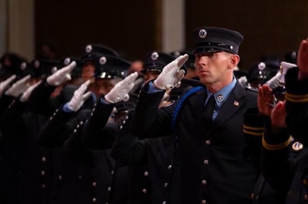 Group of people saluting at the EMS graduation at the Christian Cultural Center.