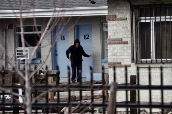 A man, Gary Oliva, standing in front of a blue door at the halfway house wher<em></em>e he is residing in Denver, Colorado after being released from prison.