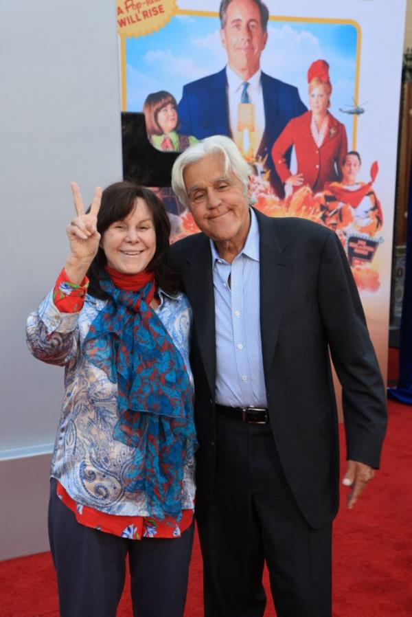 Jay Leno and Mavis Leno smiling and making peace signs at the premiere of Unfrosted on the red carpet at the Egyptian Theatre, Los Angeles.