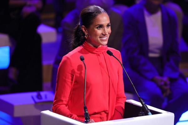 Meghan, Duchess of Sussex, delivering the keynote speech at the One Young World Summit 2022 in a red dress standing at a podium.