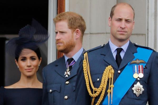 Prince William, Prince Harry, and Meghan, Duchess of Sussex, standing on the balcony of Buckingham Palace during a military fly-past.