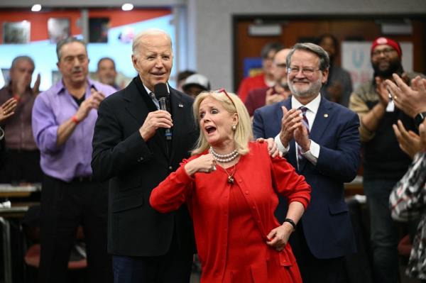 Democratic Representative from Michigan Debbie Dingell (C) gestures as President Joe Biden speaks to members of the United Auto Workers (UAW) at the UAW Natio<em></em>nal Training Center, in Warren, Michigan, on February 1, 2024.