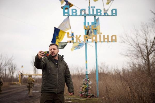 Zelenskiy takes a video in front of a road sign with the words 