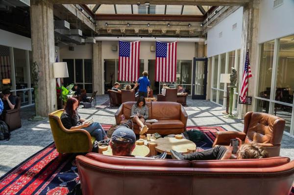 Student sitting in chairs or couches and studying, reading books or scrolling through their phones.