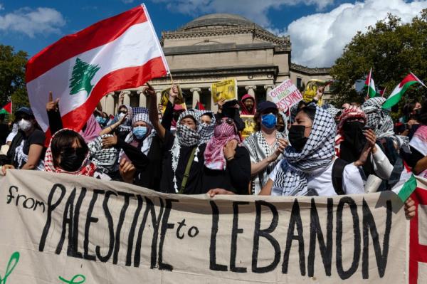 Columbia students wearing face masks protest with flags and signs on campus.