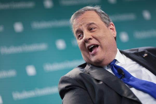 Close-up of Christie speaking at an event with a blue background. 