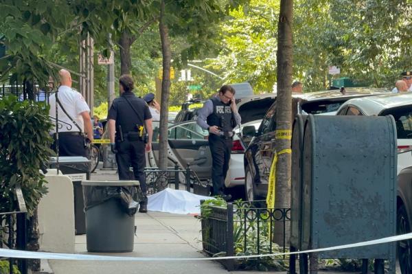 Police officers on the sidewalk of East 88th Street, Upper East Side, Manhattan, near the scene of a shooting incident involving two women.