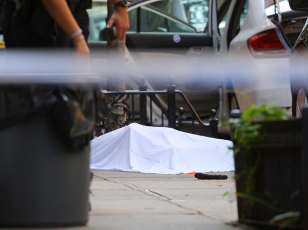 Body under white sheet with gun in foreground