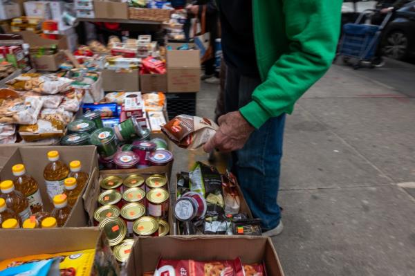 People shopping for food in a Brooklyn neighborhood with a large immigrant and elderly population. Boxes of food visible.