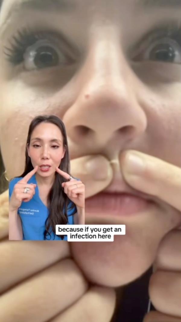 A woman touching her face, presumably to pop a pimple