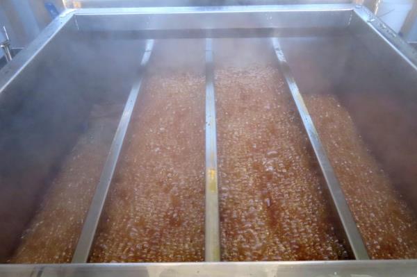 Steam rising from a cooker filled with dark, rich maple syrup at Stockton University's Galloway N.J. campus