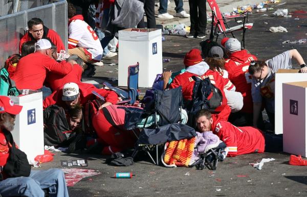 People huddling on the ground wearing red jerseys during the Kansas City Chiefs Super Bowl victory parade which ended in a deadly shooting