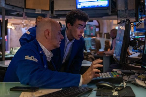 Traders at the New York Stock Exchange floor reviewing data on a computer, after Dow rallied over 400 points in September 2024.