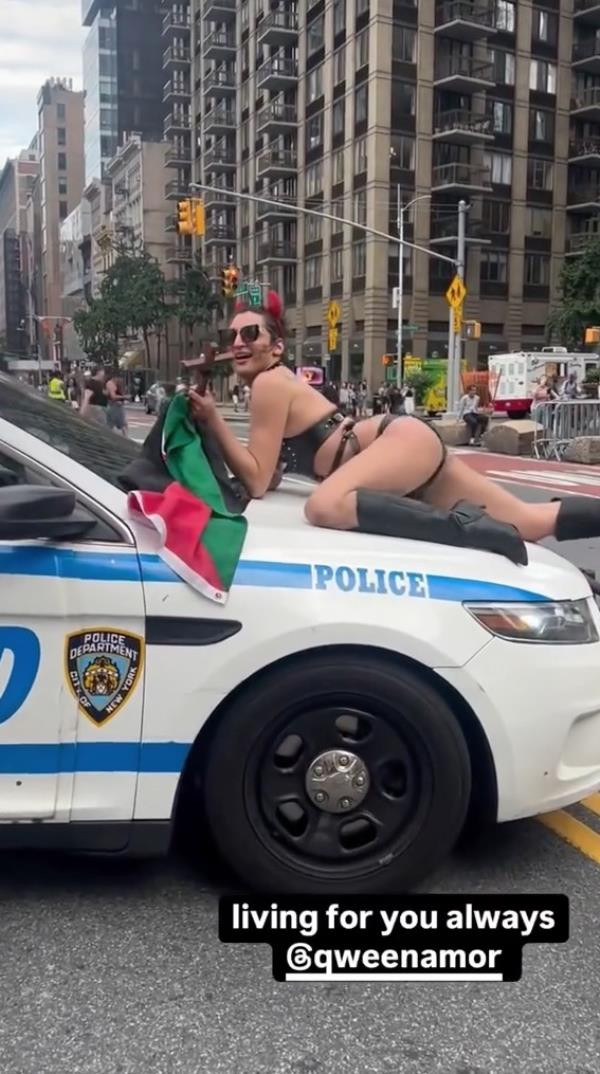 A nearly naked woman on the hood of an NYPD car holding a Palestine flag.