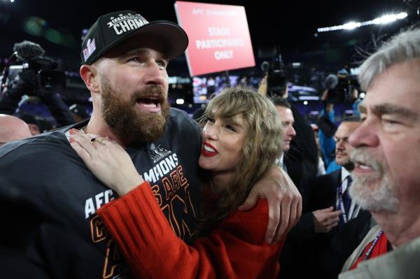 Travis Kelce #87 of the Kansas City Chiefs celebrates with Taylor Swift after a 17-10 victory against the Baltimore Ravens in the AFC Champio<em></em>nship Game at M&T Bank Stadium on January 28, 2024 in Baltimore, Maryland. They smile together. 