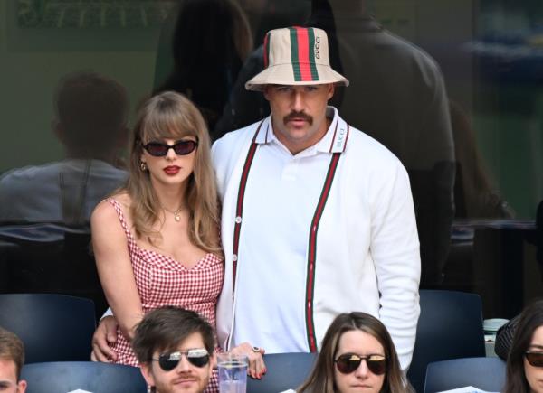 Taylor Swift and Travis Kelce together while Kelce wears a ridiculous bucket hat. 