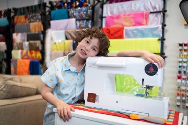 Max Alexander leans against sewing machine