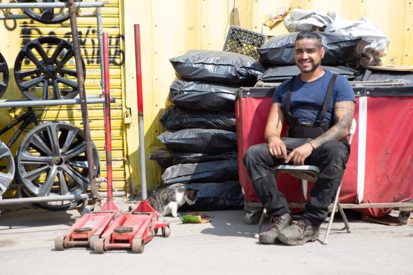 Felix Lara sits beside a cat at his shop.