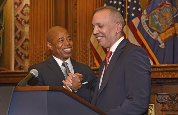 Louis Molina and Eric Adams shake hands at a podium